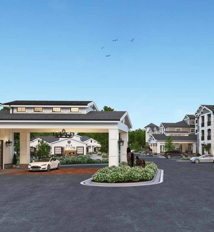 A view of a residential complex with multiple buildings and a central driveway entrance.