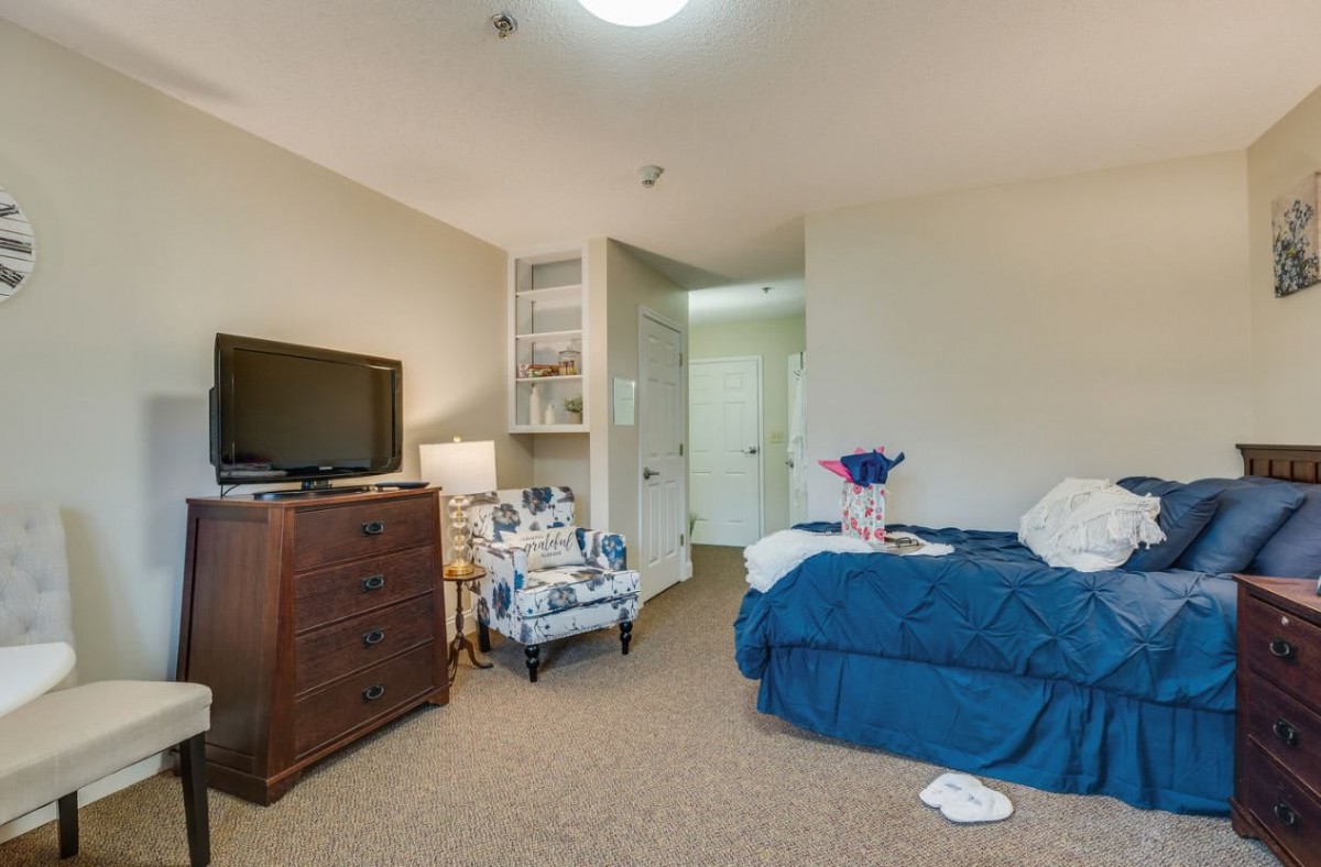 A cozy bedroom interior with a bed, television, and comfortable seating.