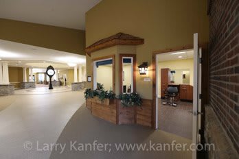 A spacious hallway with a clock and an open door leading into a room.