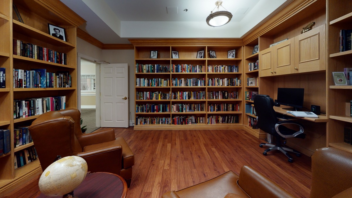 A cozy home library with wooden bookshelves and comfortable seating.