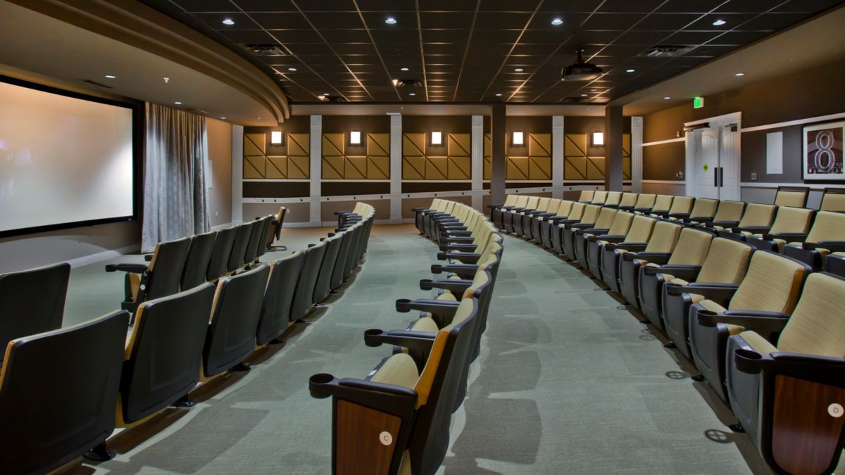 An empty auditorium with rows of tiered seating and ambient lighting.