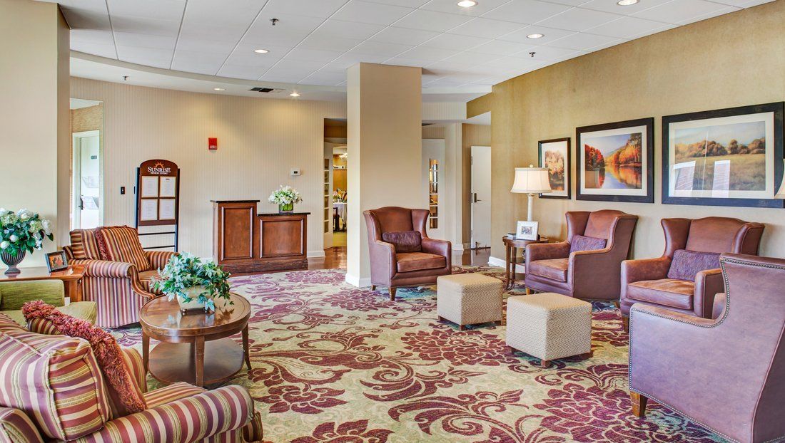 A warmly decorated hotel lobby with comfortable seating, elegant carpet, and framed artwork on the walls.