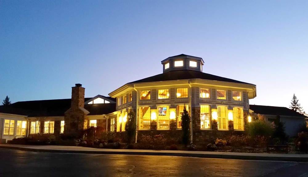 A well-lit building with large windows during the evening.