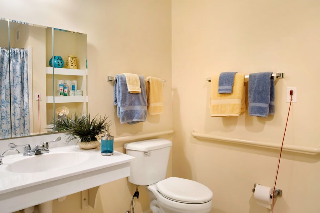 A neatly organized bathroom with a toilet, sink, and colorful towels.