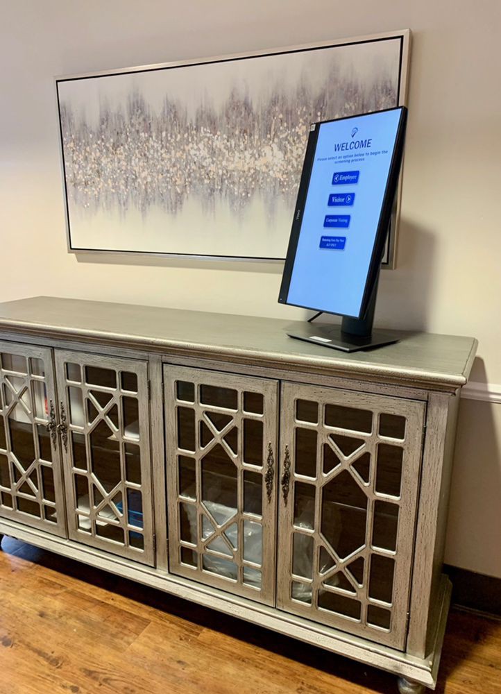 An elegantly designed mirrored cabinet with a touchscreen device on top, set in a well-decorated room.