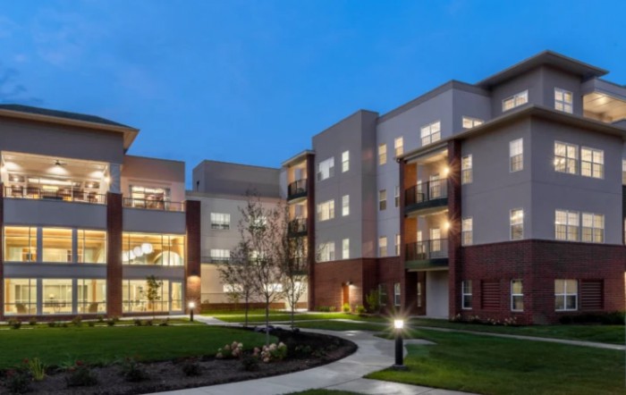 A modern apartment complex with illuminated windows and a courtyard at night.
