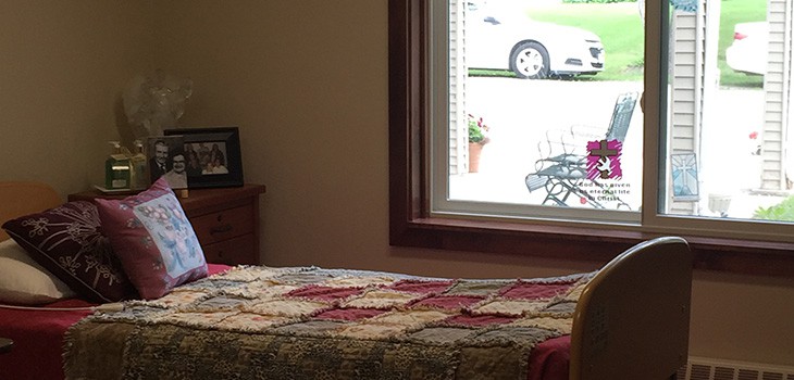 A cozy bedroom with a quilted bedspread and a view of the outdoors through the window.