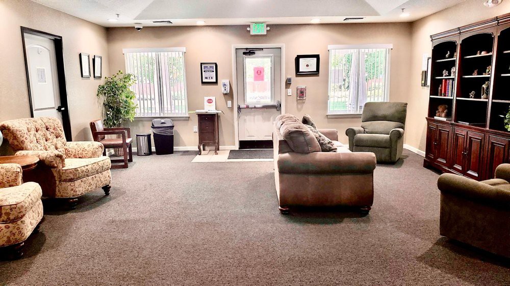 A cozy waiting room with comfortable seating, large windows, and soft lighting.