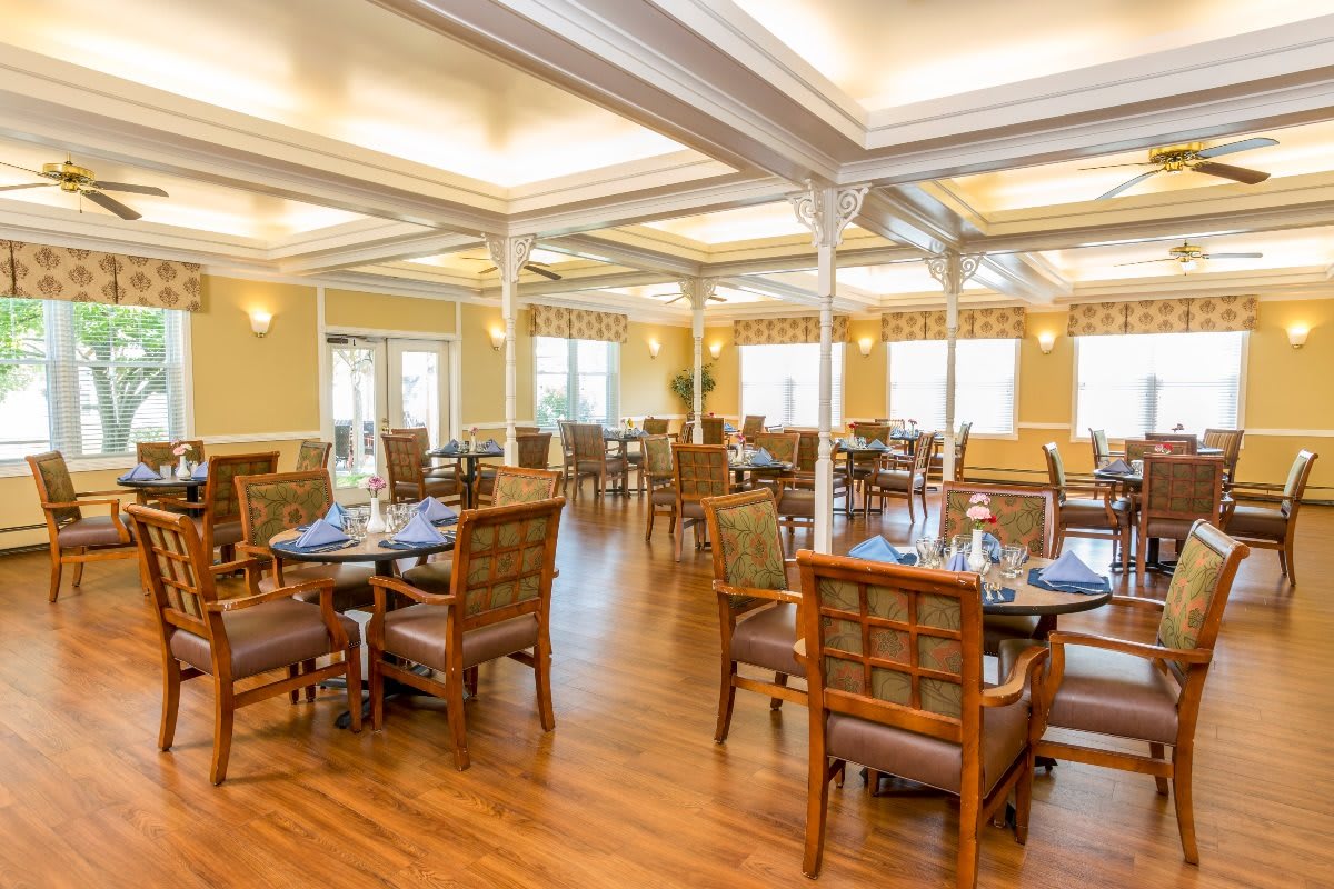 Spacious dining area with neatly arranged tables and chairs, featuring elegant lighting and wooden flooring.