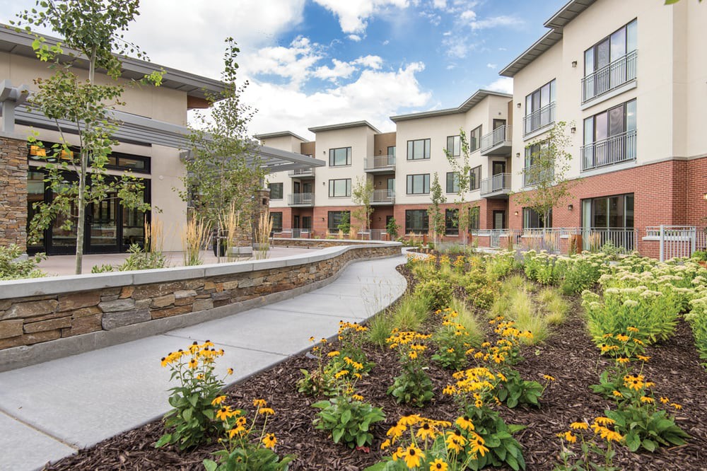 A modern apartment complex with well-maintained gardens and a winding pathway.