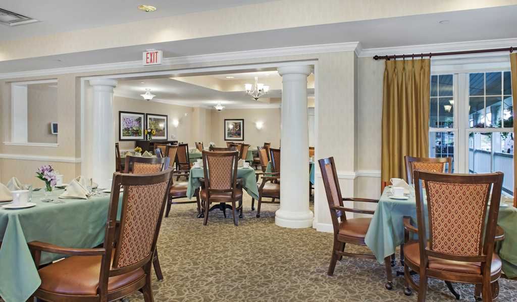 A spacious dining room with elegantly set tables and chairs, featuring a warm and inviting atmosphere.