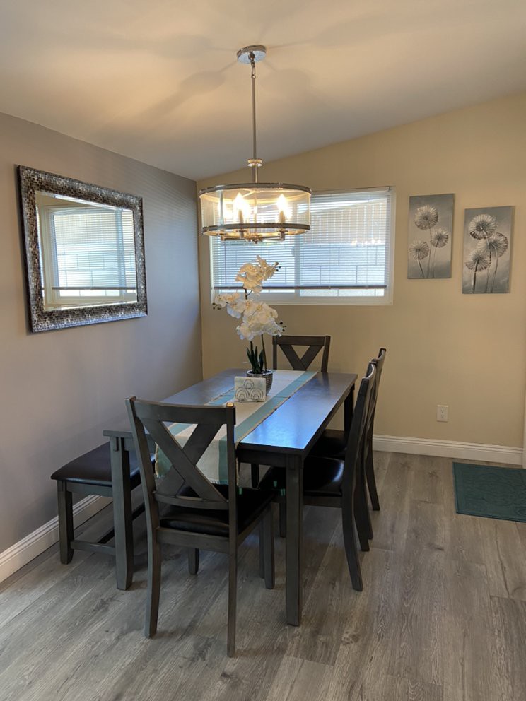 A cozy dining room with a dark wood dining set, elegant chandelier, and tasteful wall decorations.