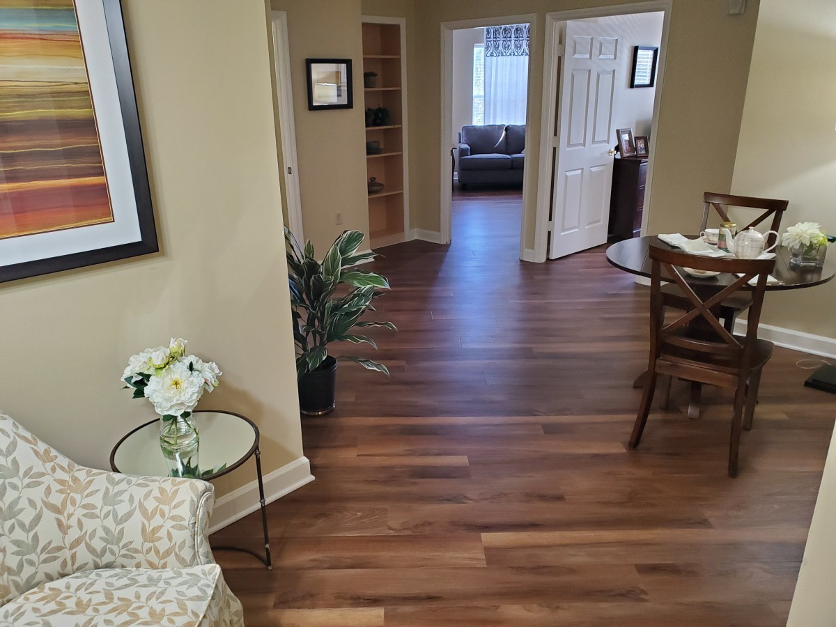 A cozy and modern living space with hardwood flooring, featuring a plant and comfortable seating.