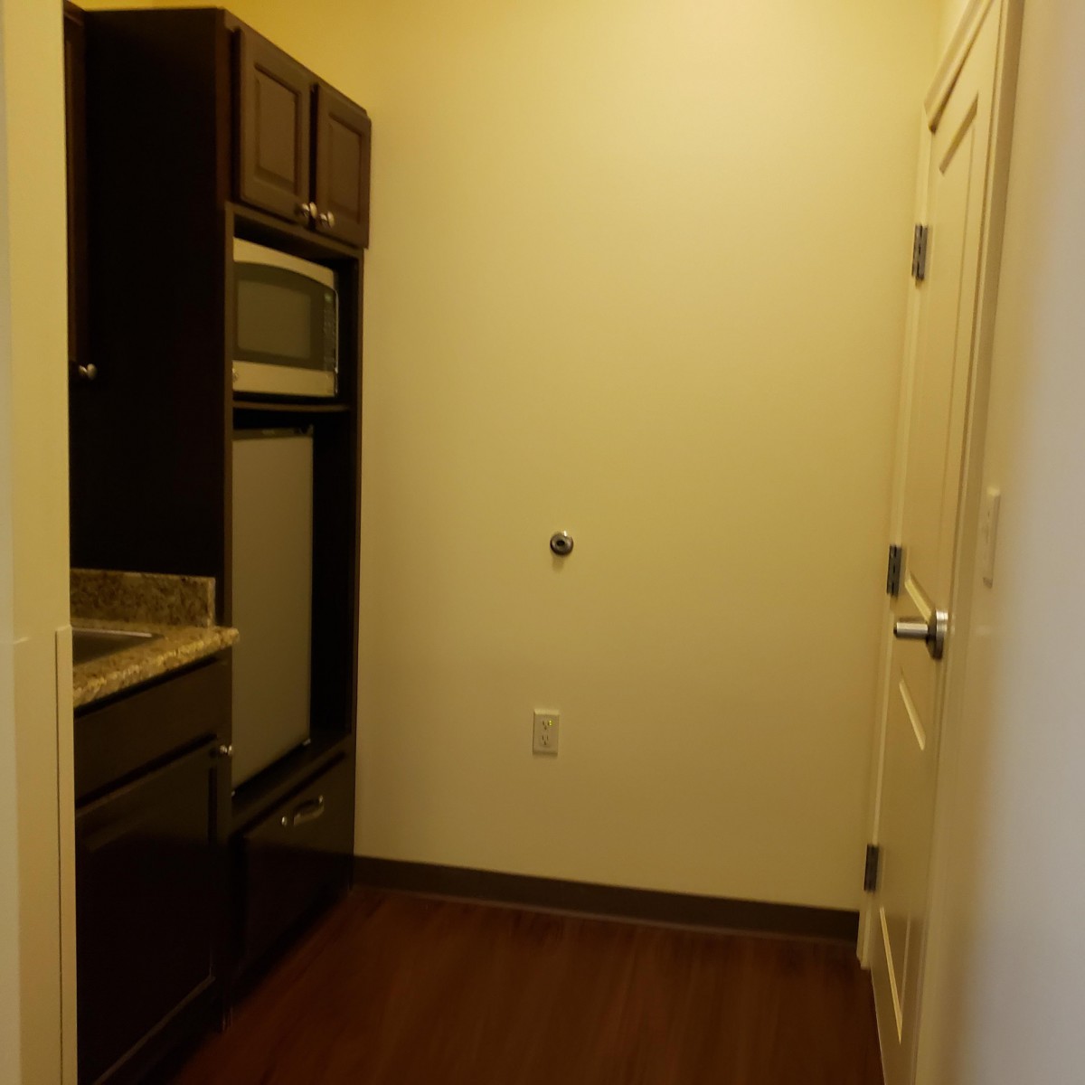 A small kitchen area with built-in appliances and dark wood cabinets.