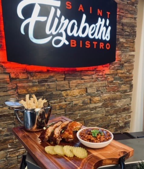 A delicious meal at Elizabeth's Bistro featuring fries, a meat dish, and beans served on a wooden platter.