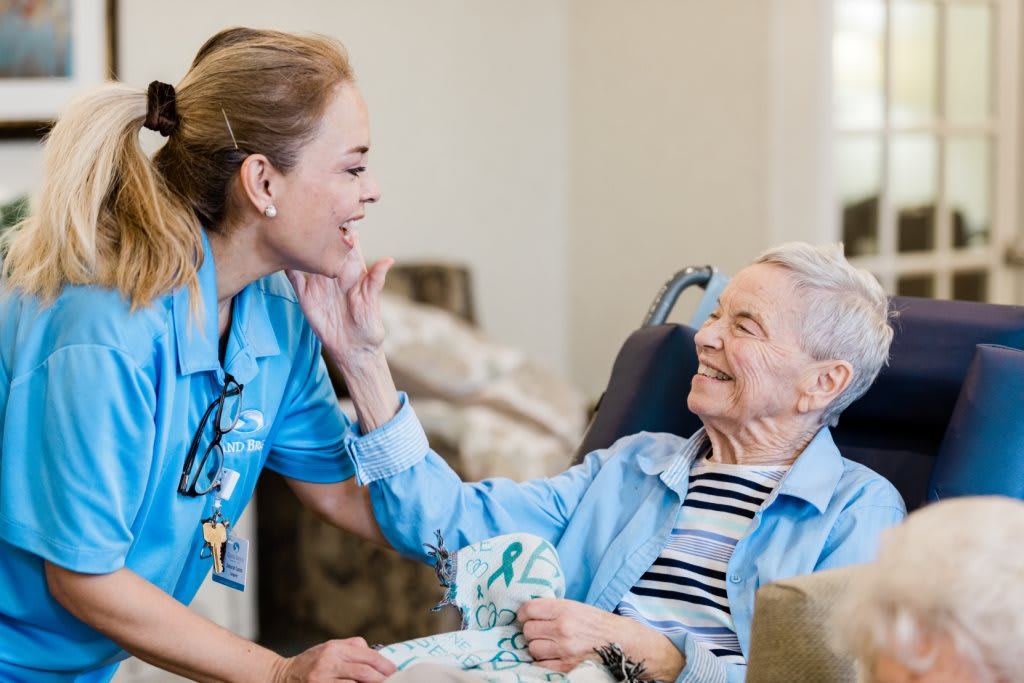 A nurse interacts warmly with an elderly patient, sharing smiles and care.