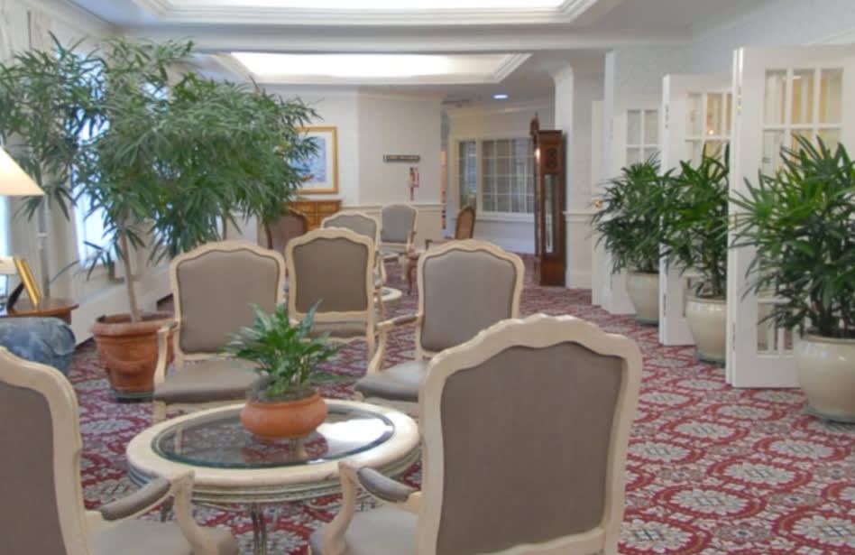 A spacious lobby area with elegant chairs, tables, and lush plants.