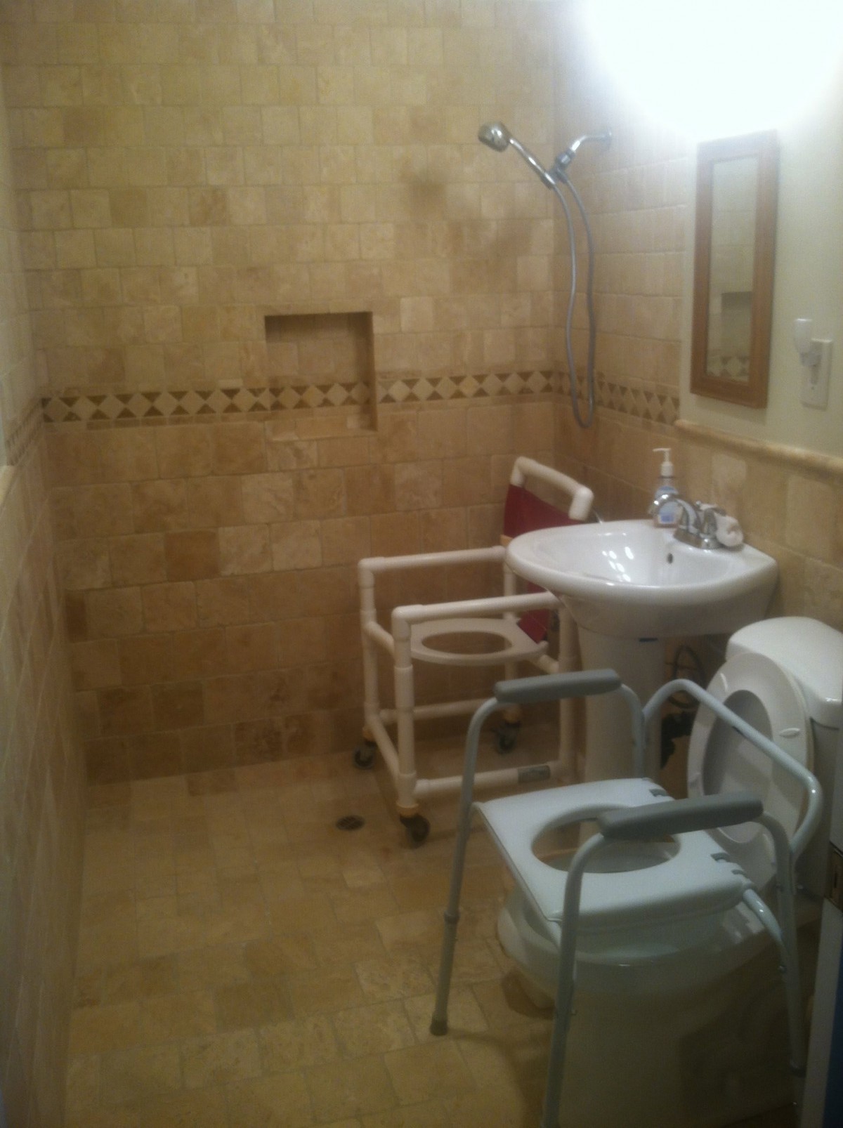A handicap-accessible bathroom with tiled walls, equipped with a sink, toilet, and grab bars.