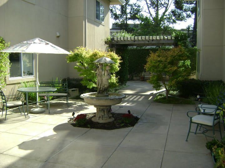A serene courtyard with a central fountain, surrounded by greenery and outdoor seating.