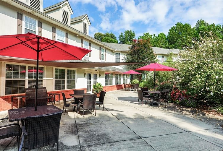 A sunny patio with tables and umbrellas outside a building.