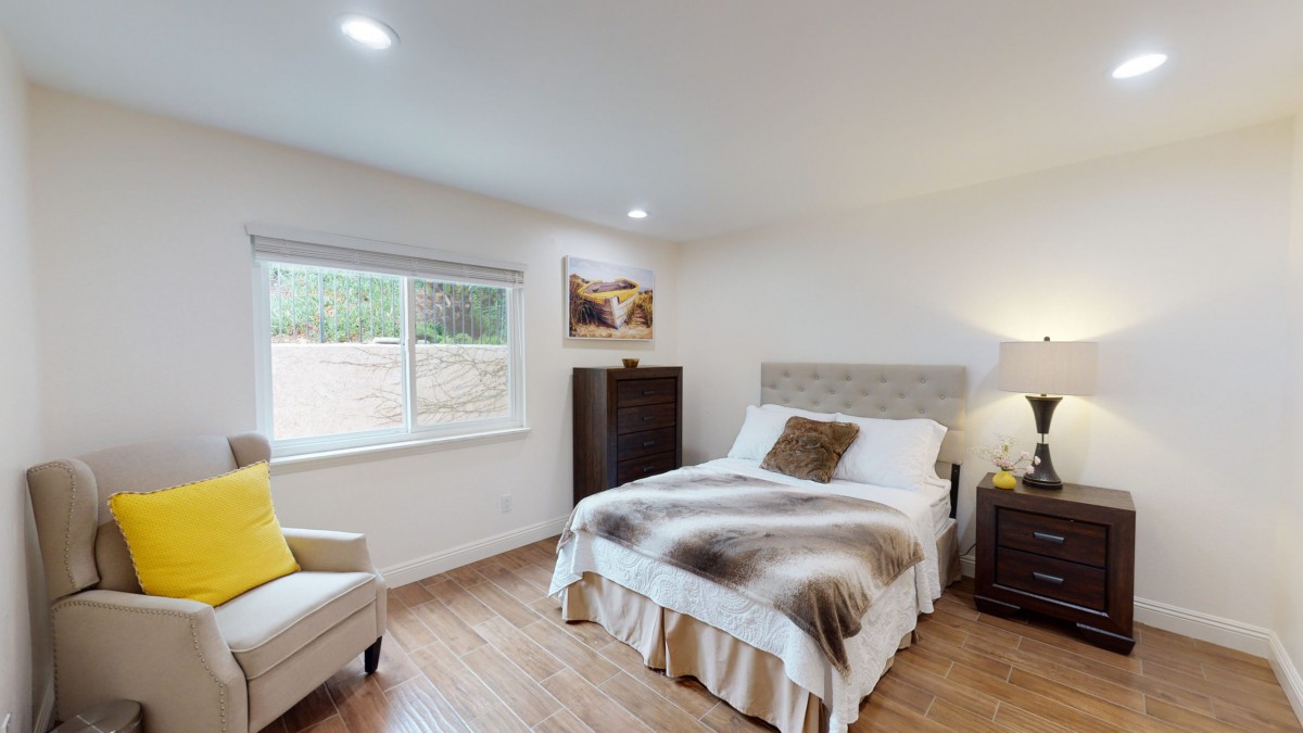 A cozy bedroom with modern decor, featuring a bed, chair, and window.