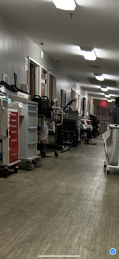 A busy hospital corridor lined with various medical equipment and trolleys.