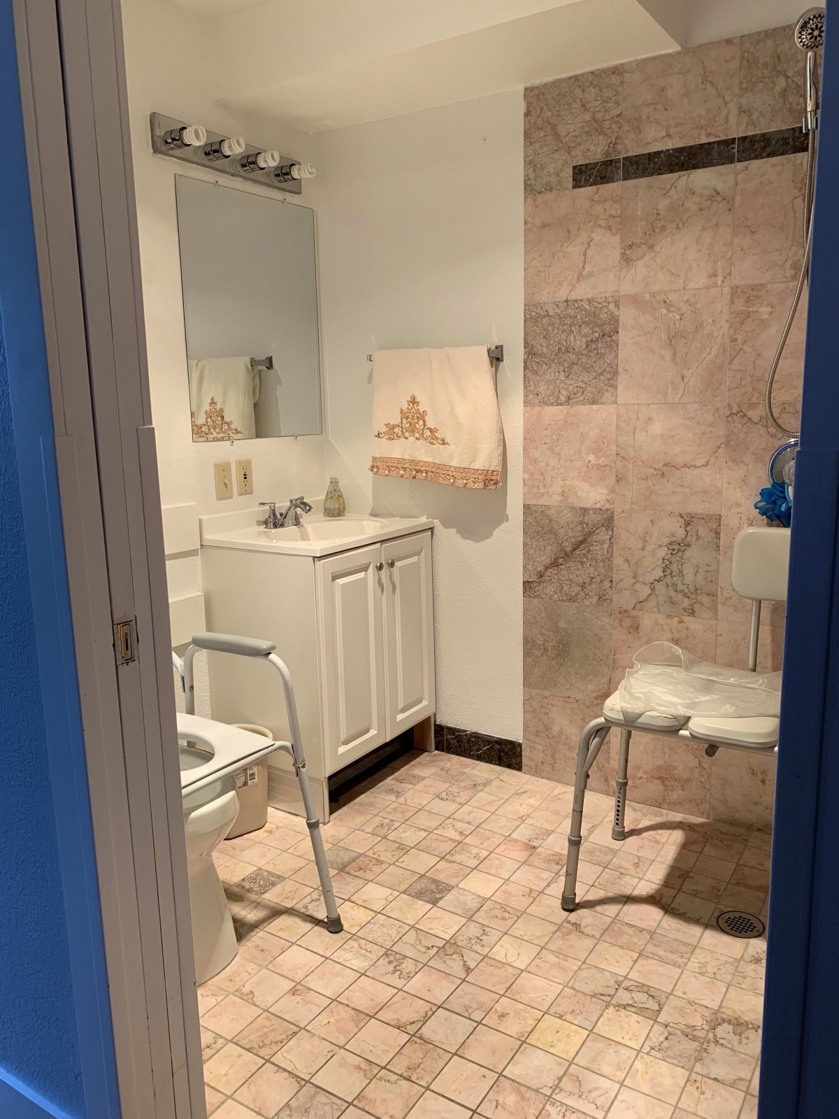 An accessible bathroom with safety features including a shower chair and handrails.