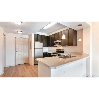 A modern apartment kitchen with stainless steel appliances and white cabinets.