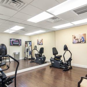 A gym with fitness equipment and mirrored walls.