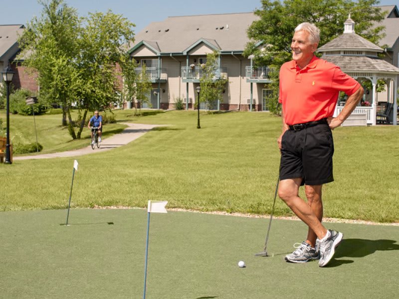 A man in casual clothing enjoys a game of golf on a sunny day.