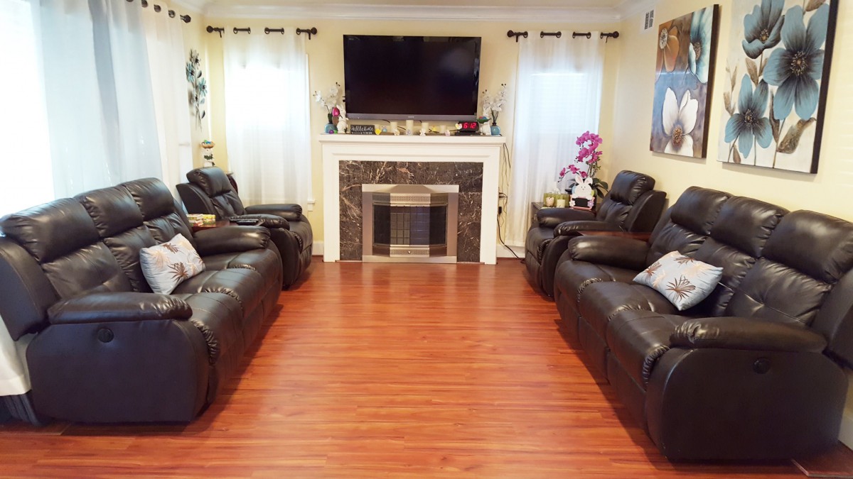 A cozy living room with leather sofas, a mounted TV above the fireplace, and hardwood flooring.