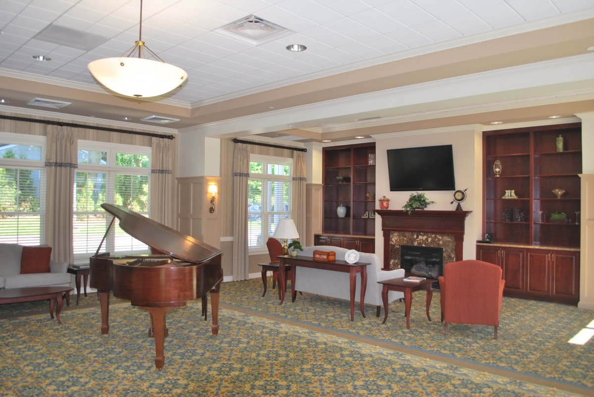 A cozy living room featuring a grand piano, fireplace, and comfortable seating arrangements.
