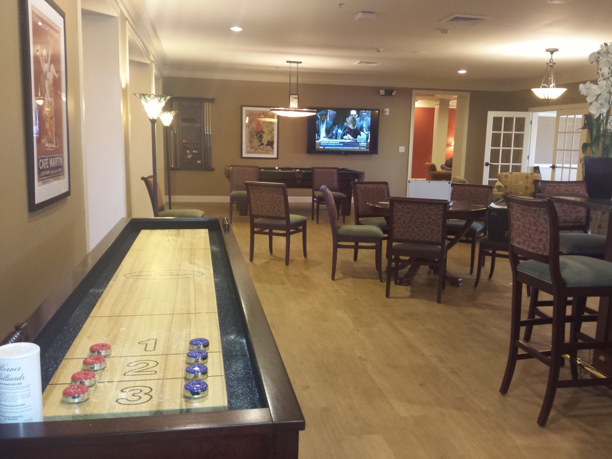 A game room featuring a shuffleboard table and a television with seating area.