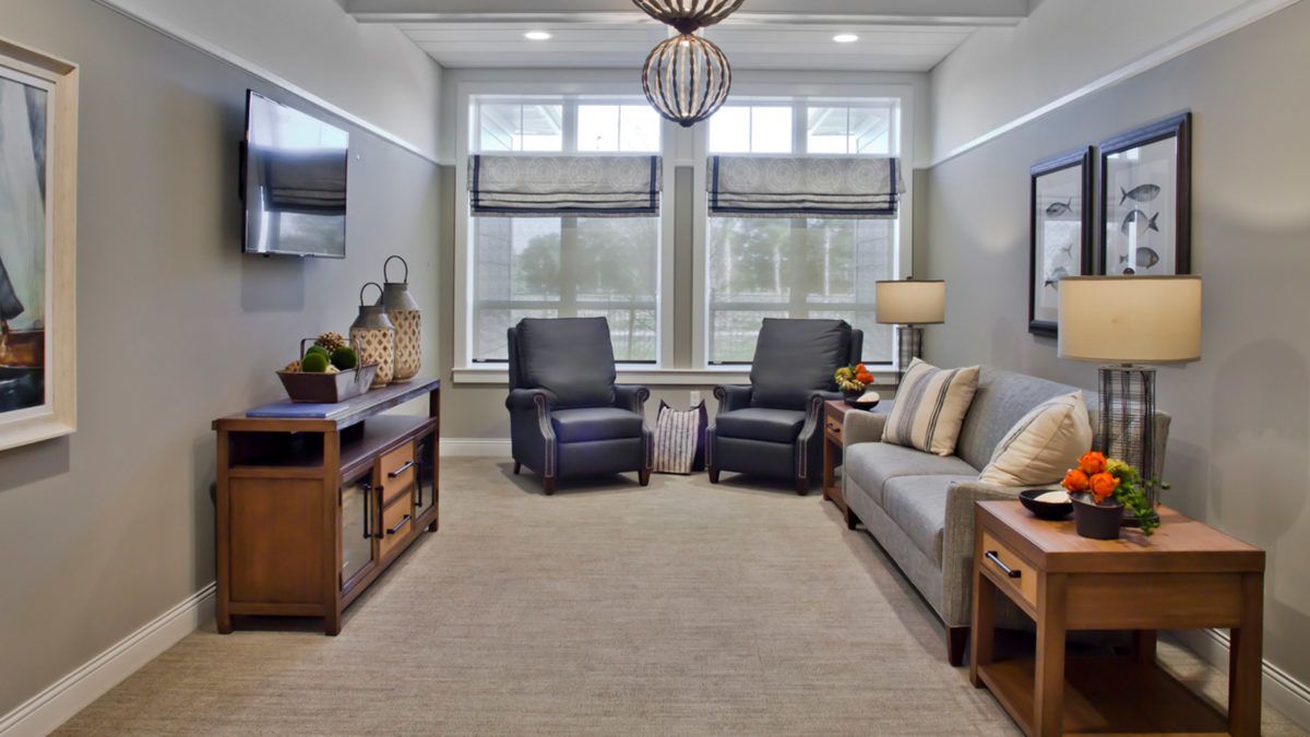 A modern living room featuring a comfortable sofa and two armchairs with large windows providing natural light.