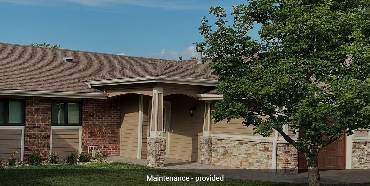 A suburban house with a garage and a tree in the front yard.