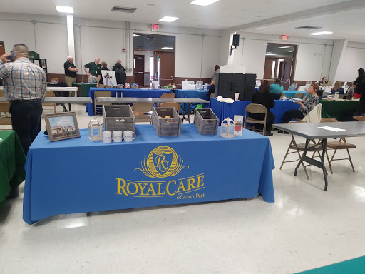 A booth displaying RoyalCare at a community event, featuring tables and chairs set up for attendees.