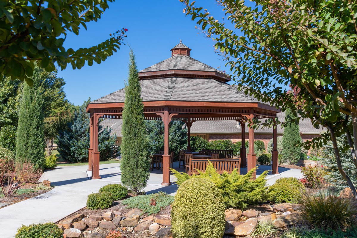 A beautiful wooden gazebo surrounded by greenery in a landscaped garden.
