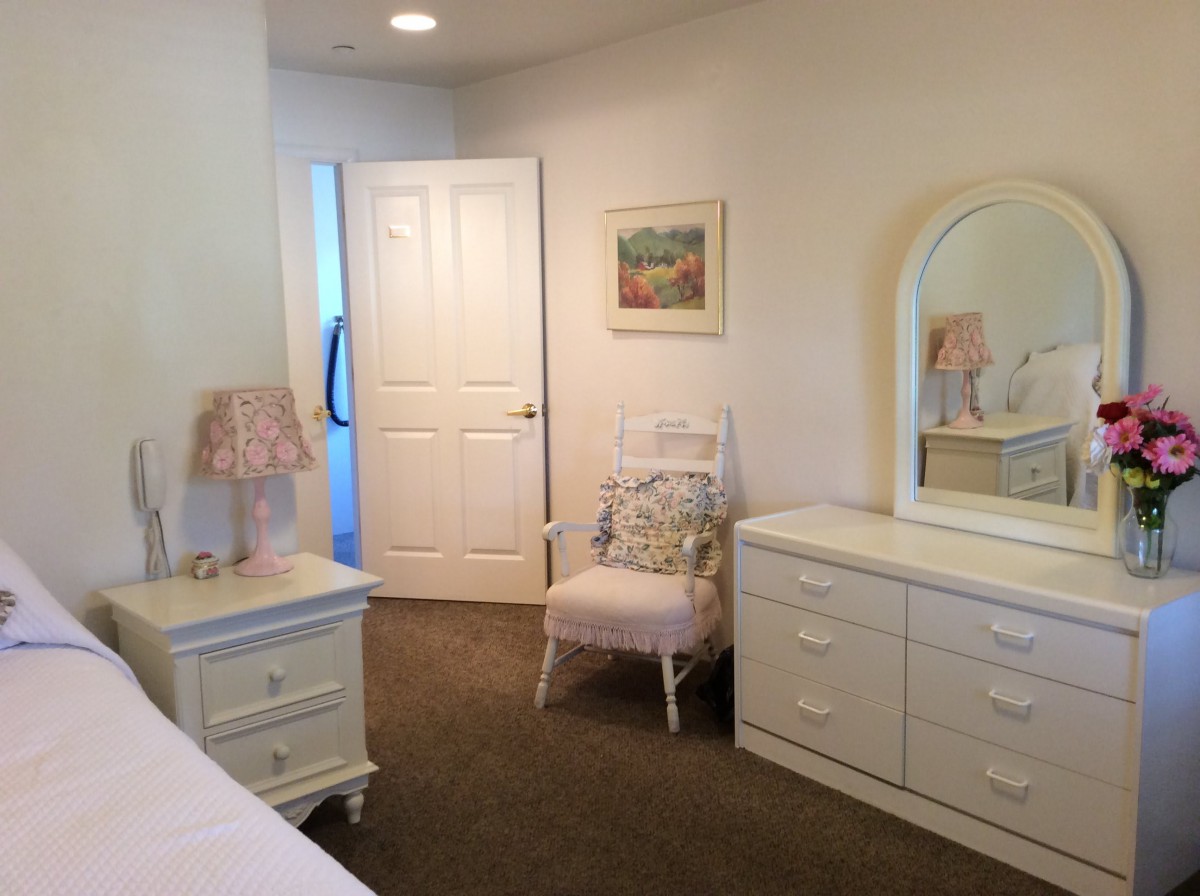 A cozy bedroom with white furniture and decor.
