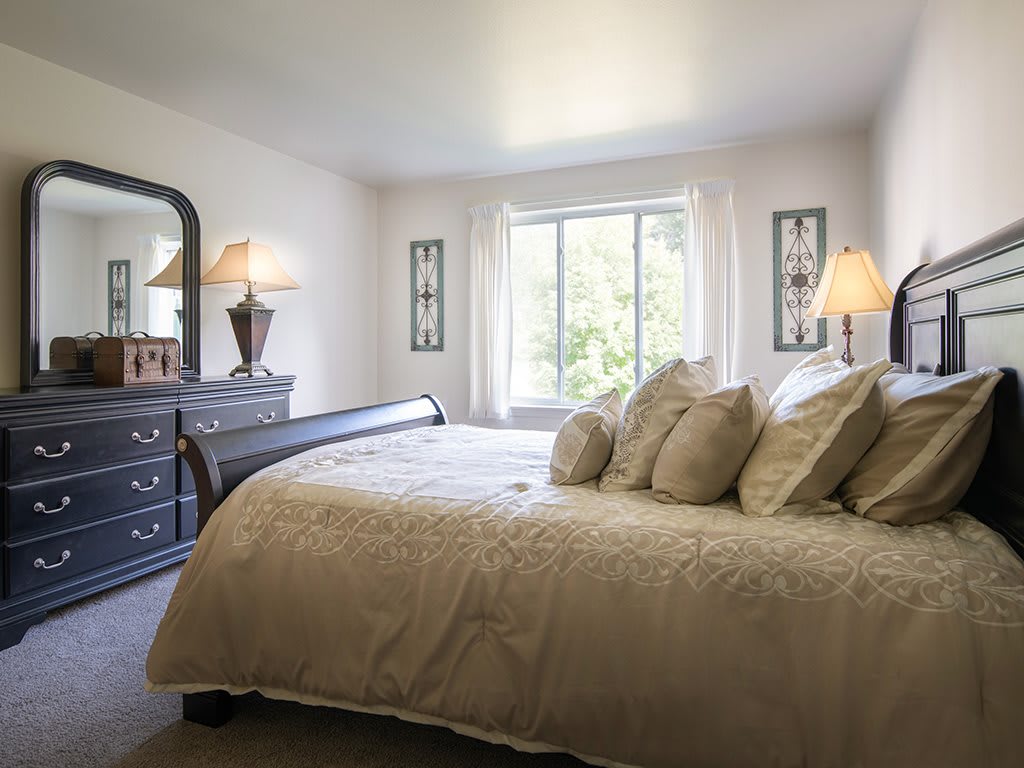 A cozy bedroom with elegant furnishings and a large window.