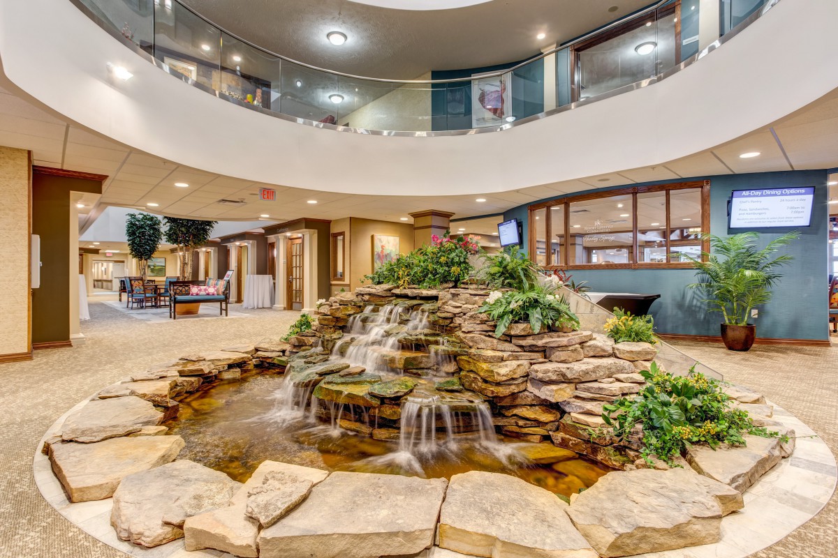 A modern lobby featuring an indoor waterfall surrounded by plants and elegant decor.