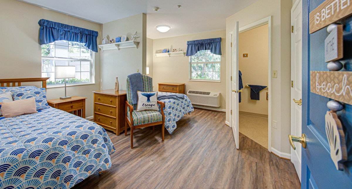 A cozy bedroom with two beds, a dresser, and a chair by the window.