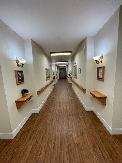 A well-lit hallway with wooden floors and decorative pictures on the walls.