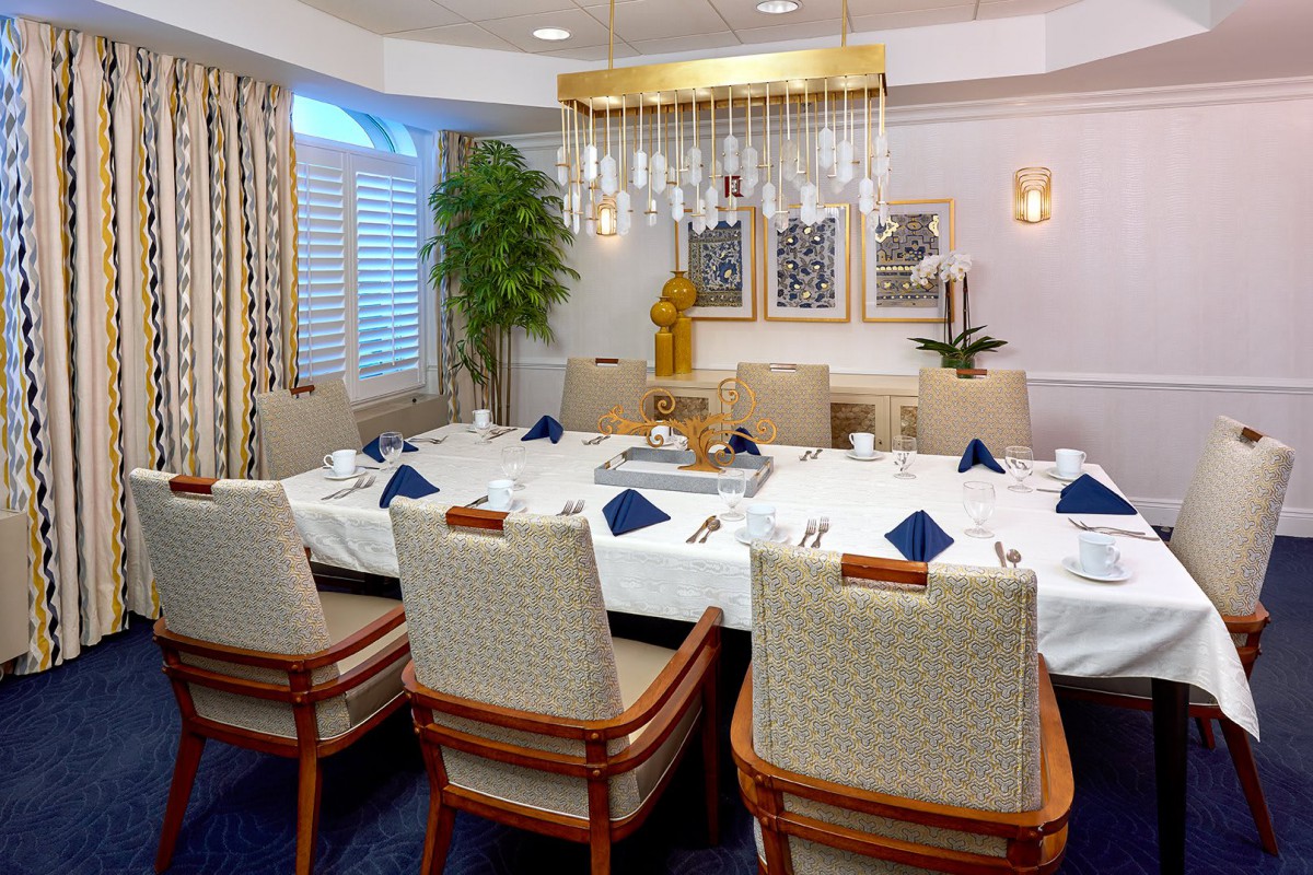 A formal dining room setup with a large table, upholstered chairs, and an elegant chandelier.