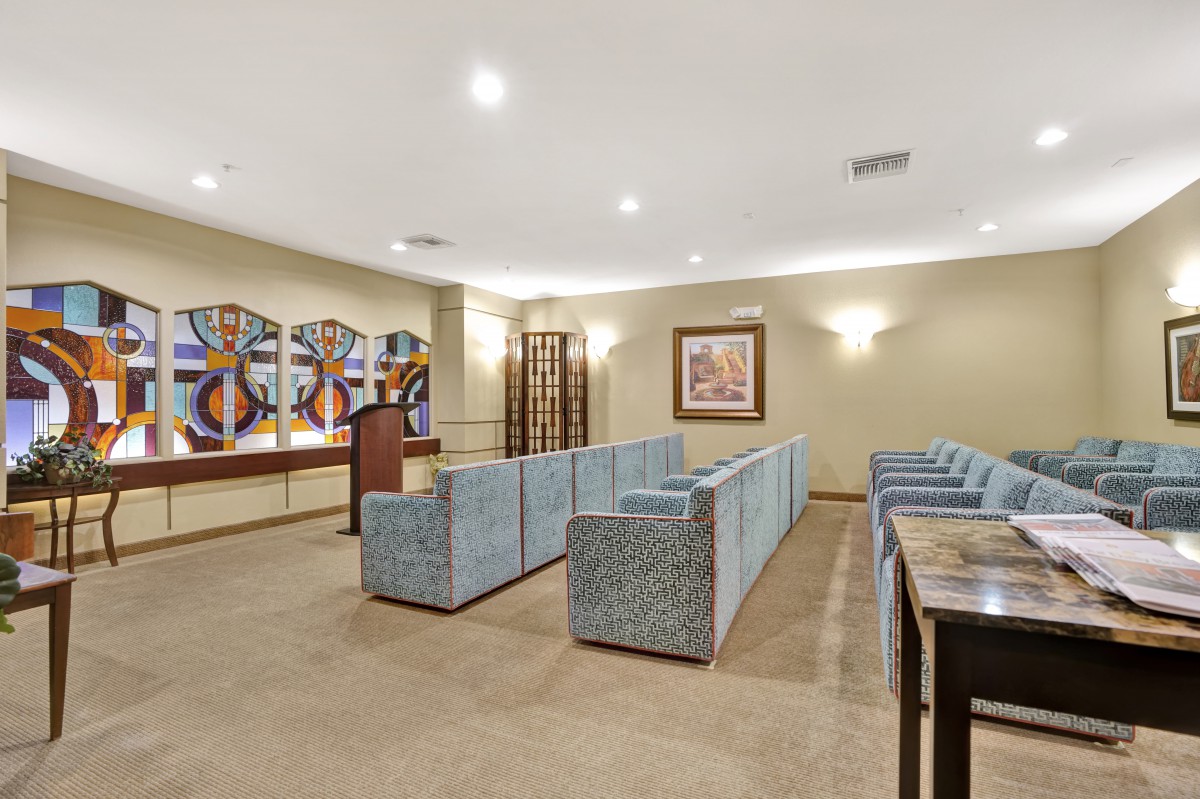 A modern meeting room with rows of upholstered seating and decorative artwork on the walls.