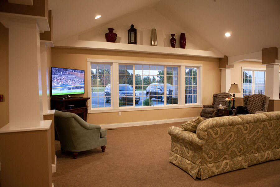 A cozy living room featuring a large window, comfortable seating, and a television.