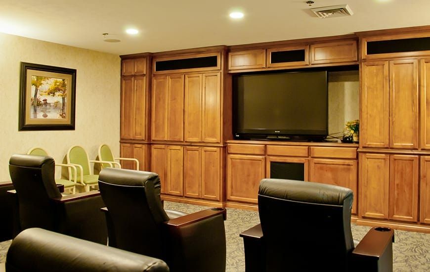 A cozy home theater setup with leather recliners and a large television surrounded by wooden cabinetry.