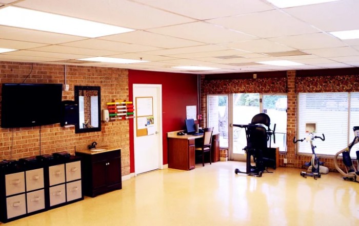 A modern office space with desks, chairs, and a computer set against a brick wall backdrop.
