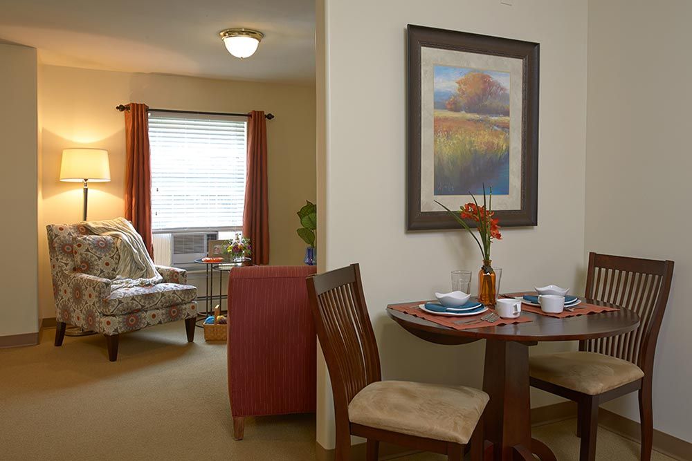 A cozy apartment interior featuring a small dining area with a table and chairs, and a comfortable living room.