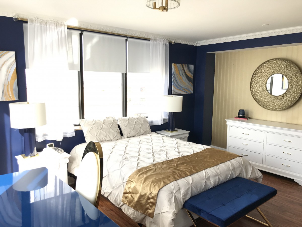 A modern bedroom with blue accents and ample natural light.