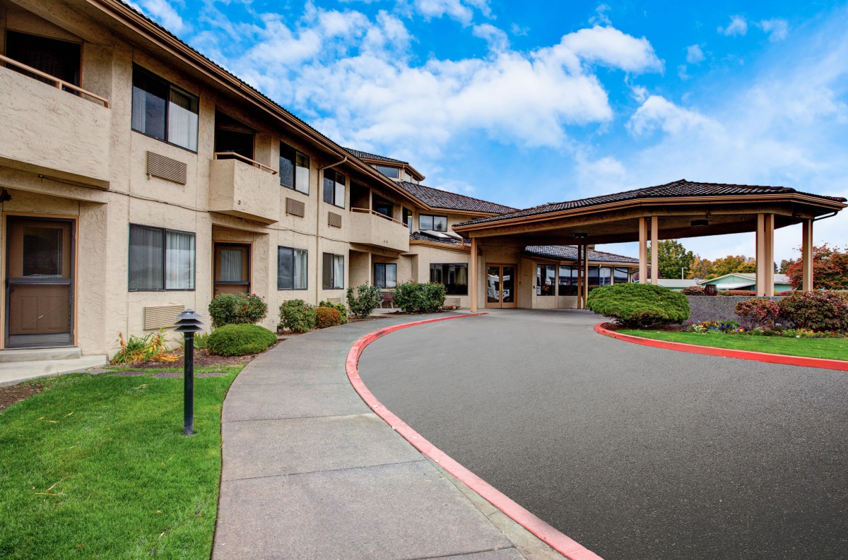 A hotel with a covered entrance and a circular driveway.